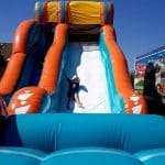 kid sliding down big kahuna inflatable water slide rental front view