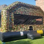 big camouflage bounce house on grass in a backyard