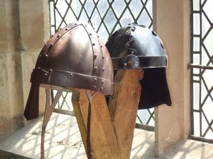 two bronze viking helmets on wooden poles 