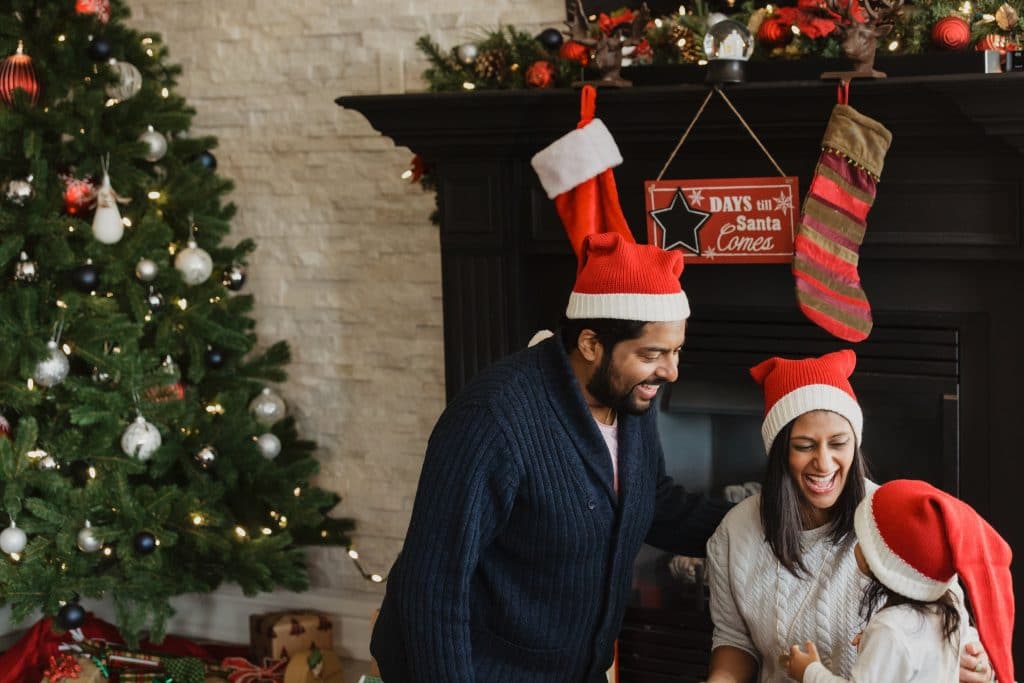 family around christmas tree wearing santa hats 