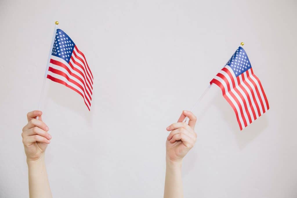 two hands waving mini American flags