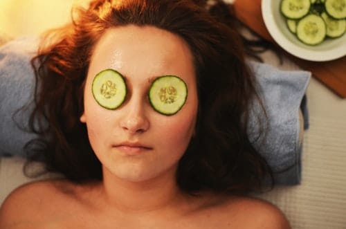 women laying down with cucumbers on her eyes