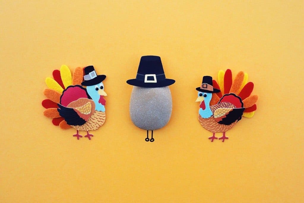 two Turkey crafts in pilgtim hats on either side of a rock also with a pilgrim hat