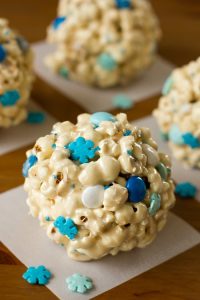 popcorn shaped into snowballs with blue candies and blue snowflake sprinkles