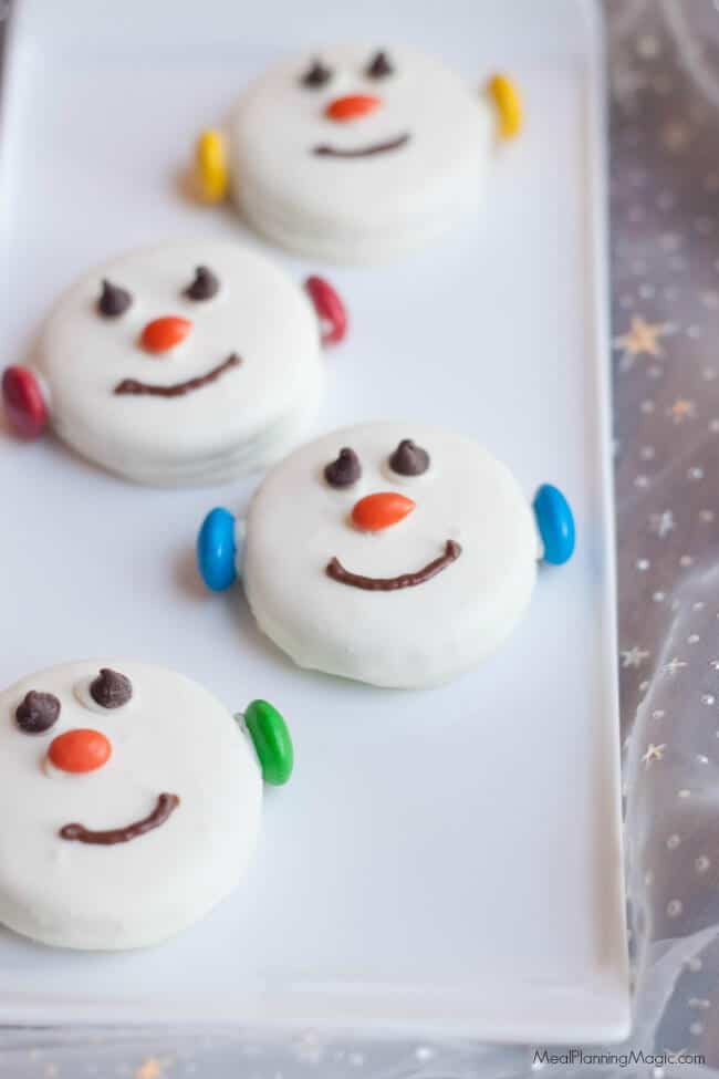 oreo cookies decorated like snowmen with eyes, orange nose, smile, and earmuffs
