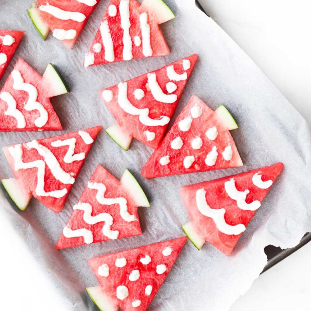 watermelon cut into triangles and decorated in yogurt to look like Christmas trees