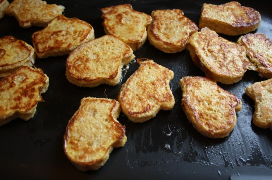 multiple French toast pieces on a skillet shaped like mittens