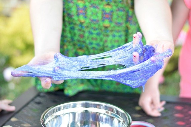 girl pulling apart glittery green slime with her hands