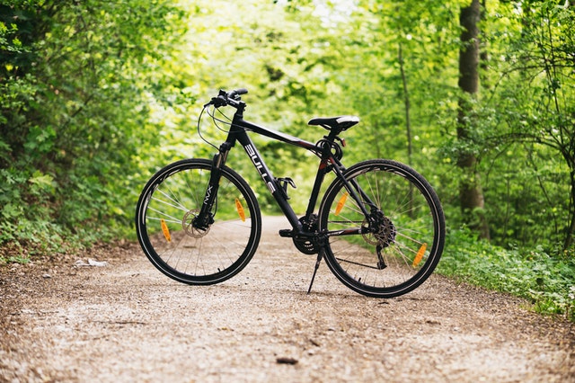 black bike bickycle on a dirt road in the middle of a forest