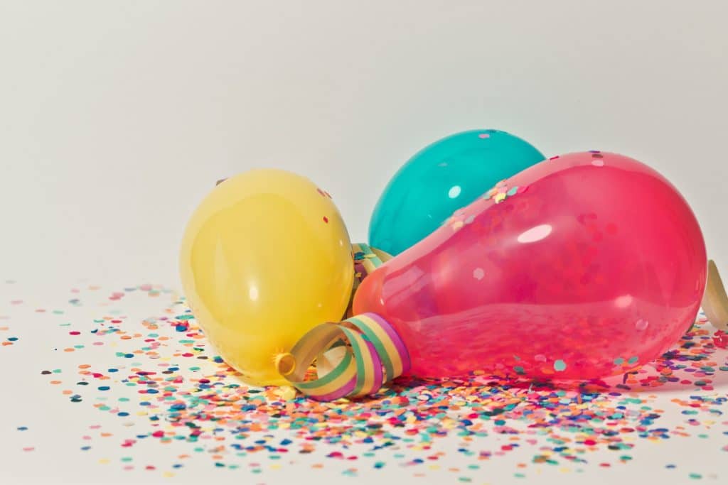 birthday party three balloons on a white surface with colorful confetti