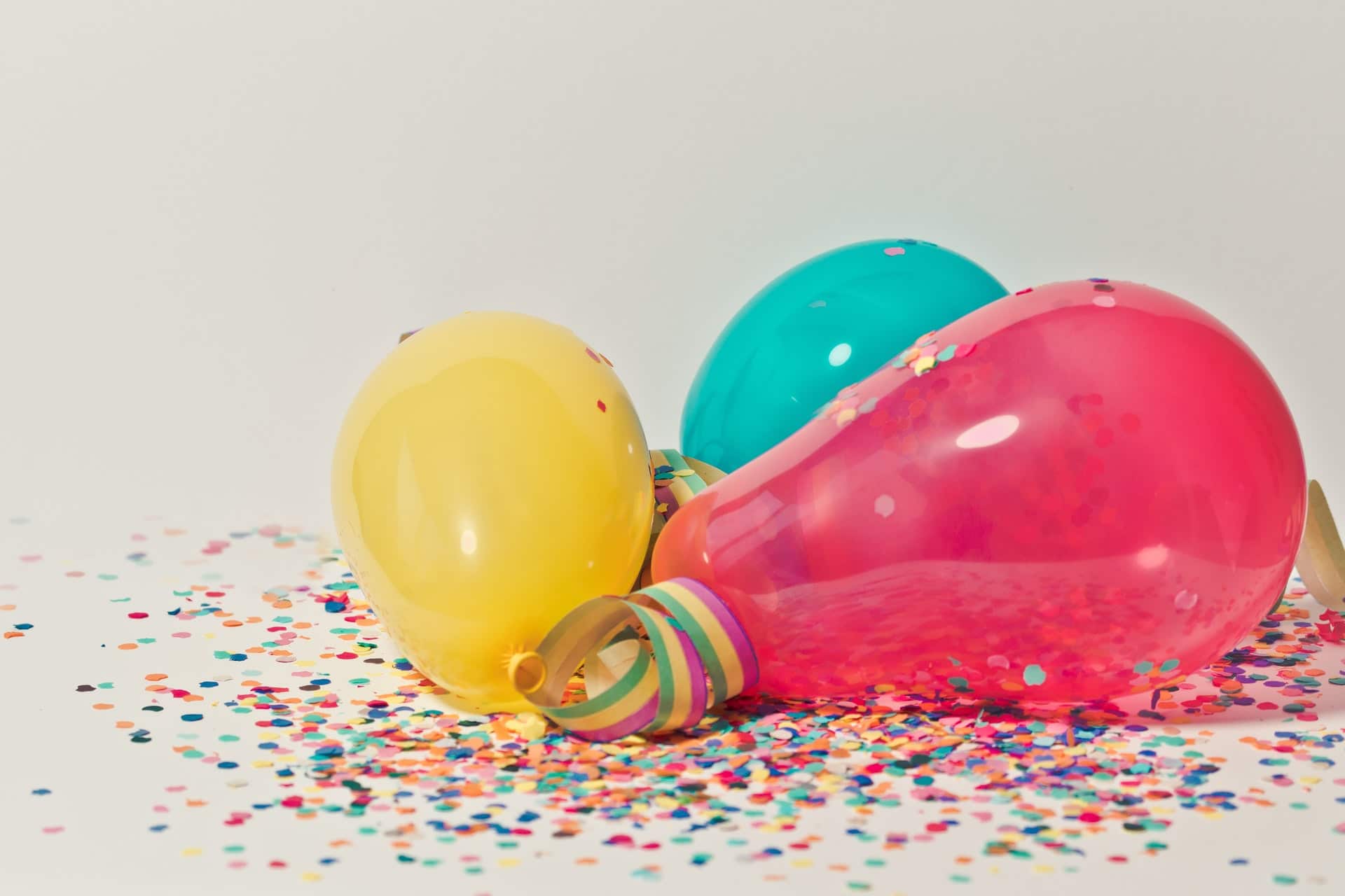 birthday party three balloons on a white surface with colorful confetti