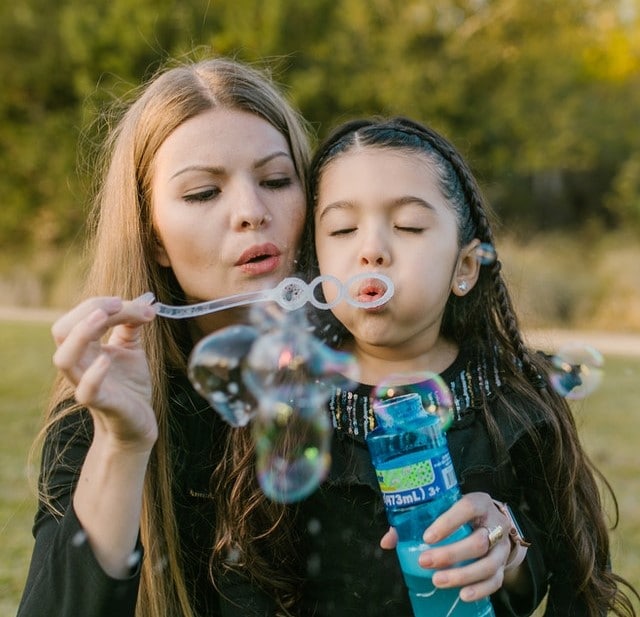 woman and her daughter blowing bubbles outside