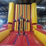 Velcro wall inflatable rental with woman standing on it with a jump suit