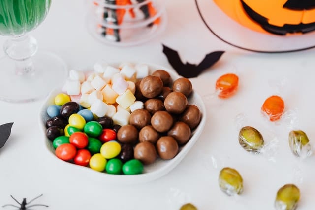 bowl of mixed candy on a table next to fall autmun Halloween decor