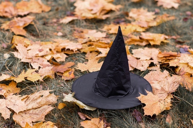 black witch hat on the ground surrounded by orange leaves