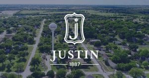 Justin, TX city logo over a picture of Justin, Texas