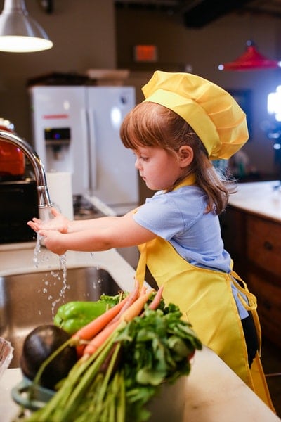 little girl in the kitchen cooking in a chef's hat and apron