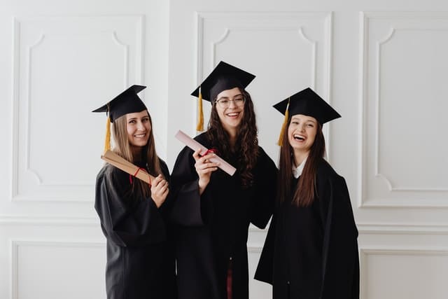three women happy in graduation gowns and caps